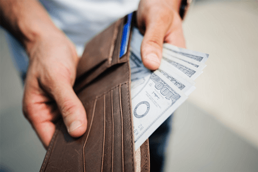 Man holding wallet out with money peaking out