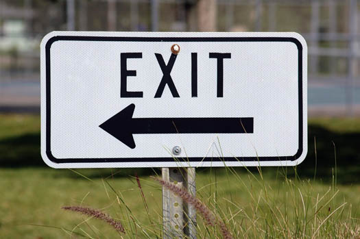 An exit sign pointing left signifying an exit strategy from a business