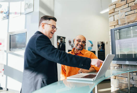 Two business men pointing at business financials on a laptop screen