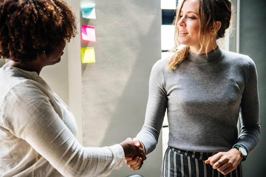 Women shaking hands over company sale agreement