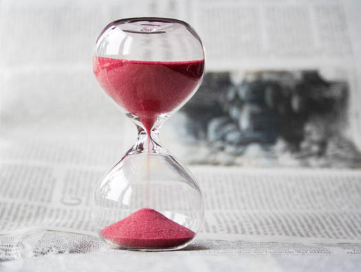 An hour glass with pink sand pouring from top to bottom