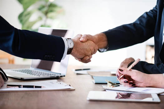 Two men in suits shaking hands after establishing internal controls