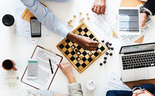 Table full of annual reports, strategic planning documents, and a chess board