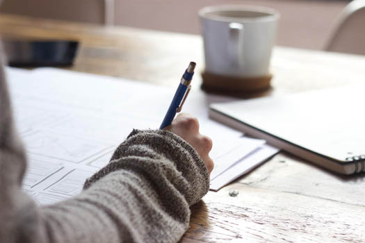 A person creating a budget on a table filled with financial documents 