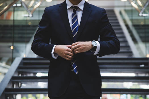 Business man wearing a blue suit and watch walking down the stairs of an office building