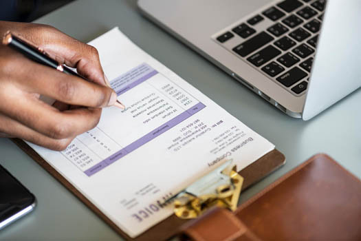 Person holding pen and filling in financial data on a clipboard